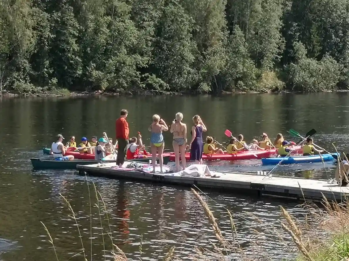 En grupp båtar ligger förtöjda vid en kanal nära Storängens camping, stugor & outdoor, omgivna av lummig grönska och vattendrag, vilket inbjuder till friluftsaktiviteter och rekreation.