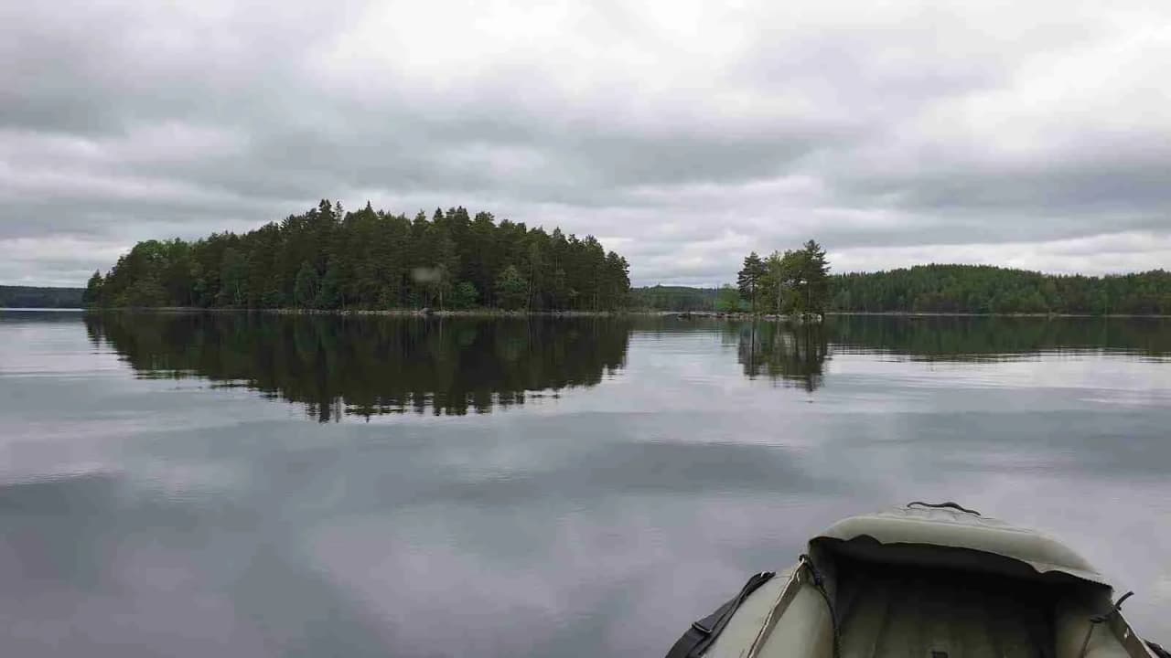 En vacker sjö med molnig himmel och en båt i fjärran vid Sandviken fribad och camping.