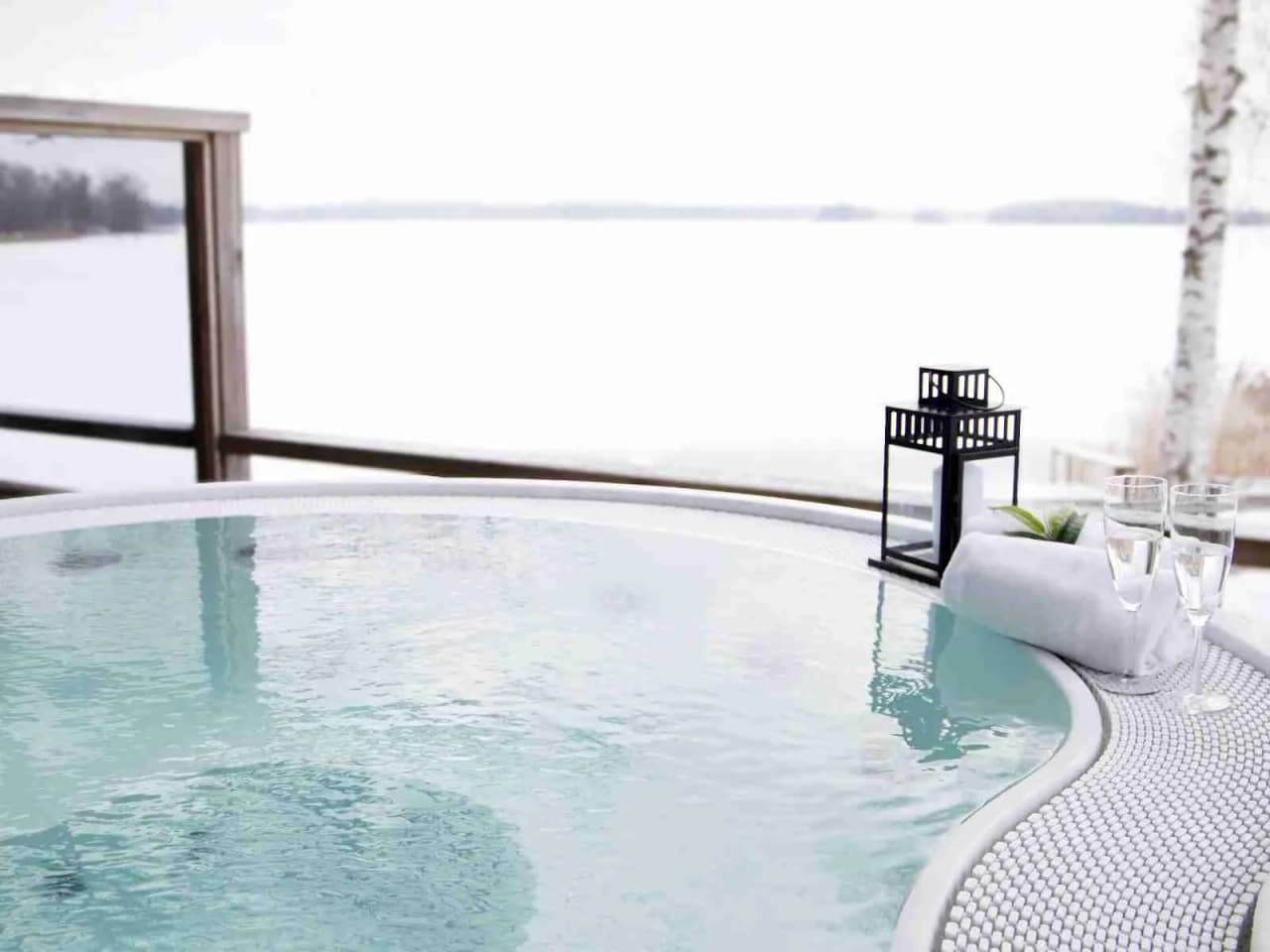 En spegelblank pool i solnedgången med en jacuzzi intill, omgiven av balkonger på ett ekologiskt hotell i Tingsryd Resort.