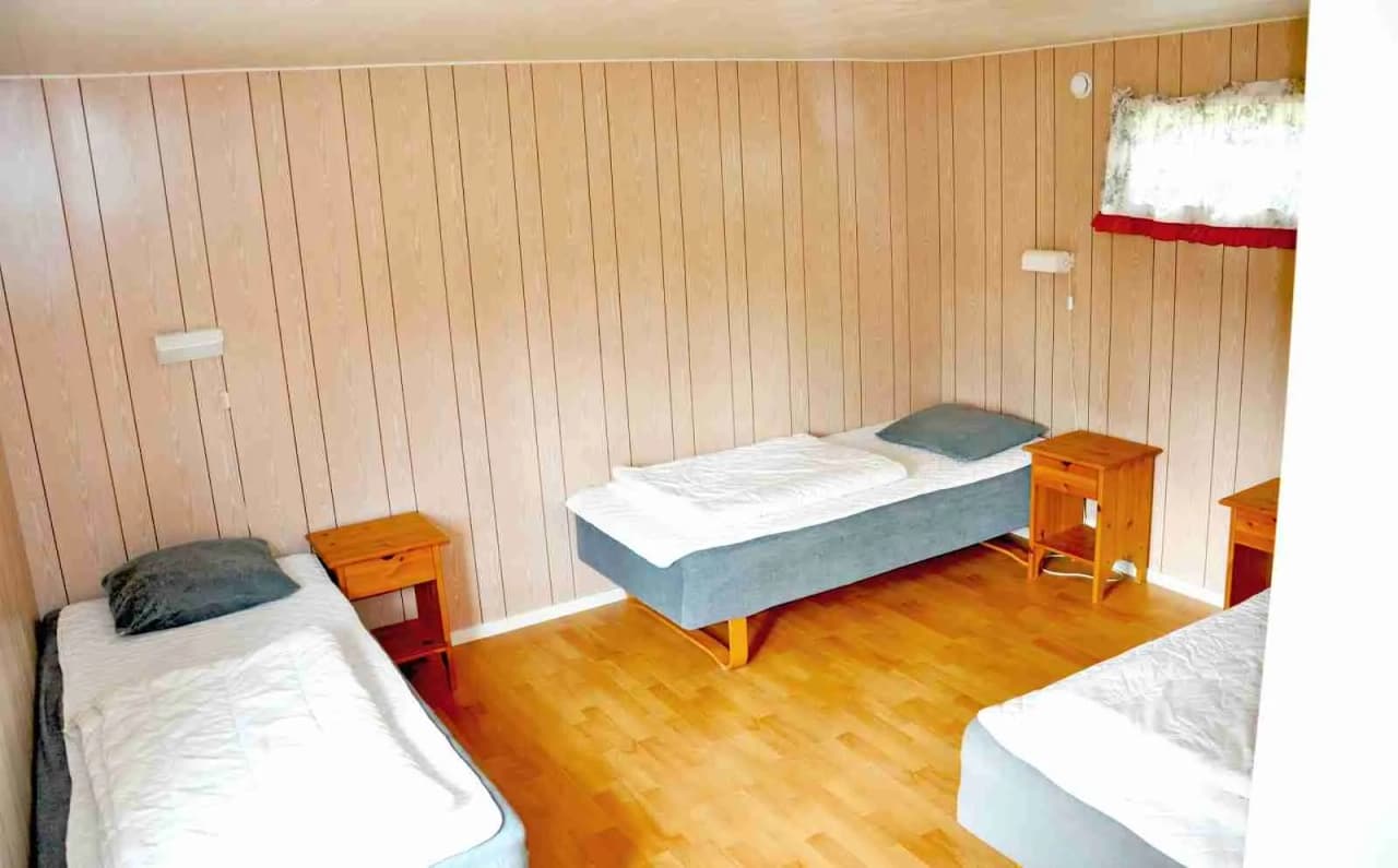 Ett rum med träinredning och ett bäddat sovrum, inklusive en säng och sängkläder, hos Åminne Fritid & Havsbad AB.