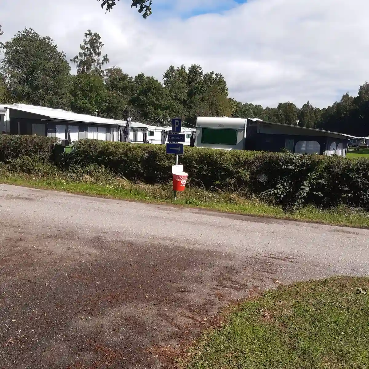 En husvagn och en husbil parkerade på en grusplan omgiven av natur vid Herrfallet AB, en plats för camping och friluftsaktiviteter.