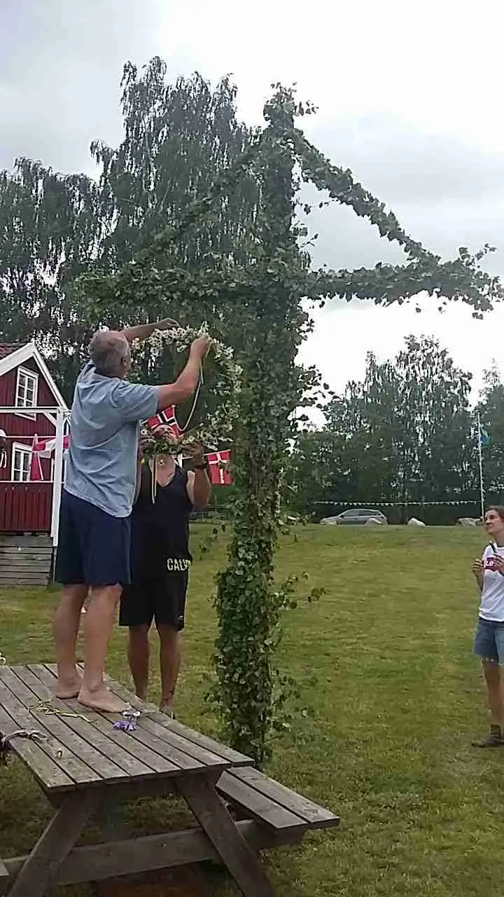 En person balanserar på ett rep vid en stolpe på Linneryds camping, omgiven av grönska och fritidsområde.