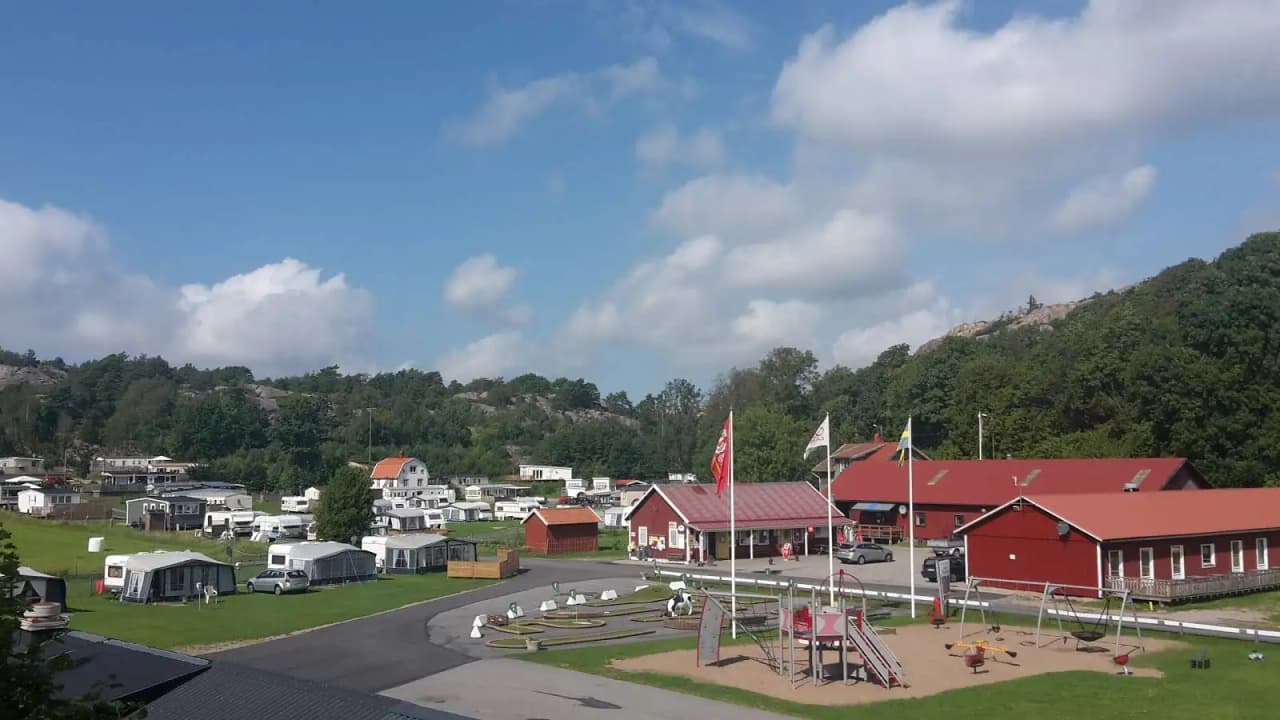 En campingplats med en flaggstång i förgrunden, omgiven av naturskön miljö.