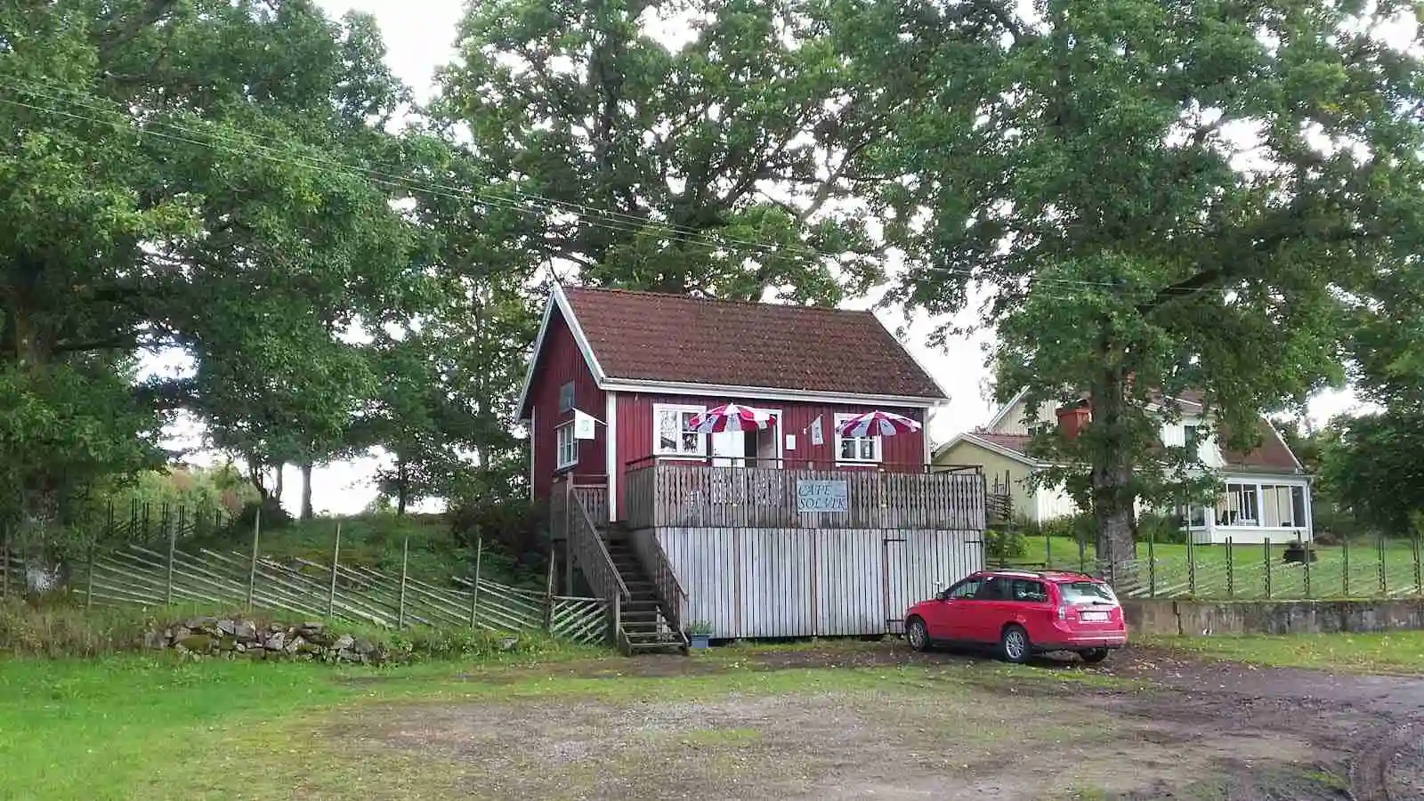En lantlig stuga med veranda omgiven av staket, belägen inom Kalvs Familjecamping. En välskött gårdsplan omger huset, vilket ger en inbjudande och avkopplande atmosfär.
