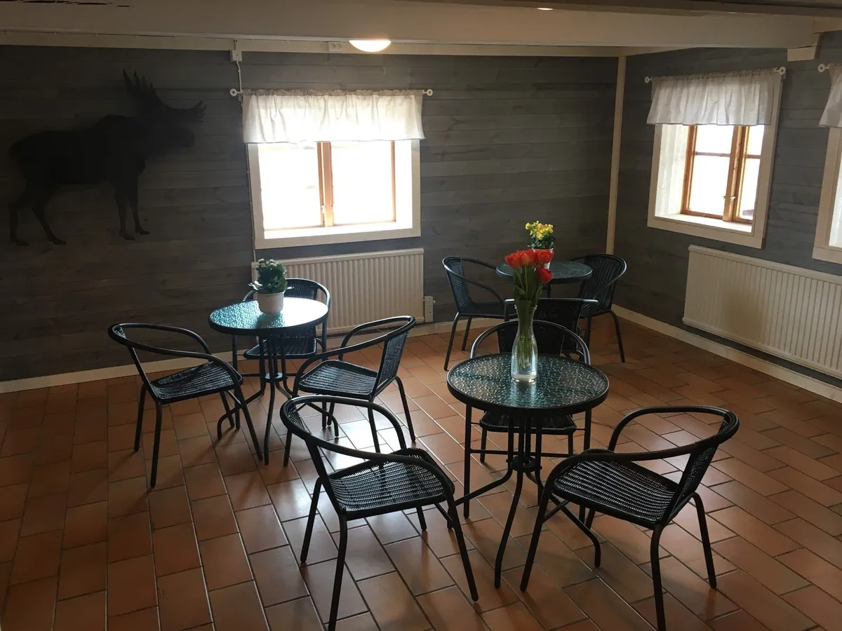 En interiörbild från Malingsbo camping, som visar ett rum med trämöbler, inklusive stolar och ett bord. Golvet och väggarna är gjorda av trä och bidrar till en rustik och inbjudande atmosfär.