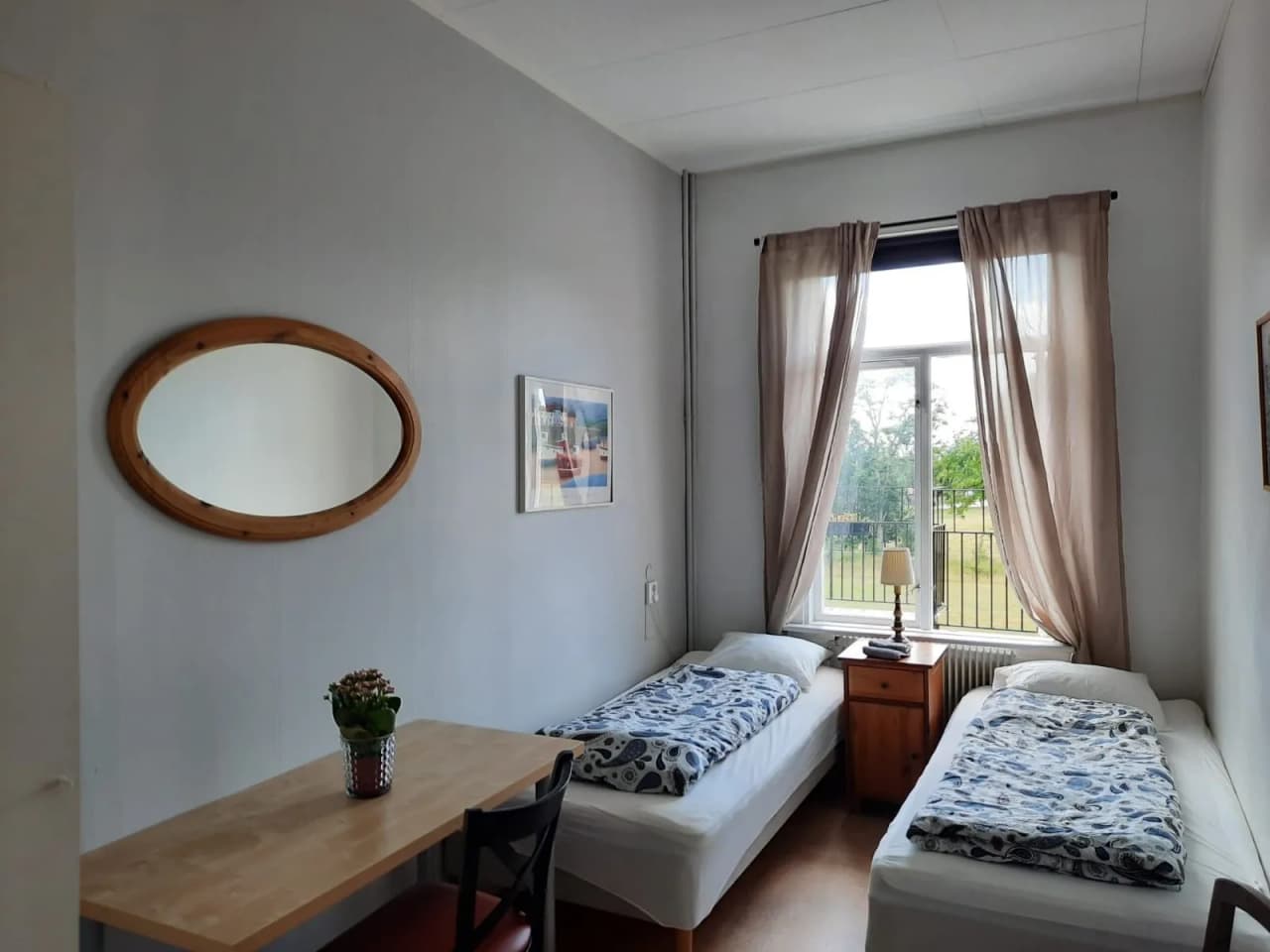 En enkel och inbjudande sovrumsmiljö med en träbädd utrustad med vita sängkläder, placerad på ett trägolv. Rummet förmedlar en rustik och hemtrevlig känsla, typisk för Hunnebergs Gård Hostel & Camping.