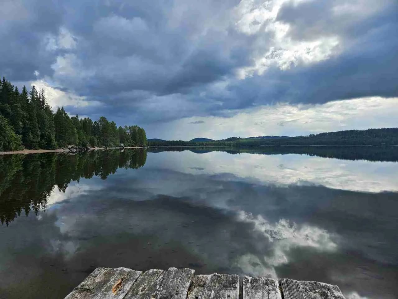 En vidsträckt blå himmel med vita cumulusmoln speglas i ett lugnt vattenlandskap, vilket ger en känsla av fridfull natur vid Camp Route 45.