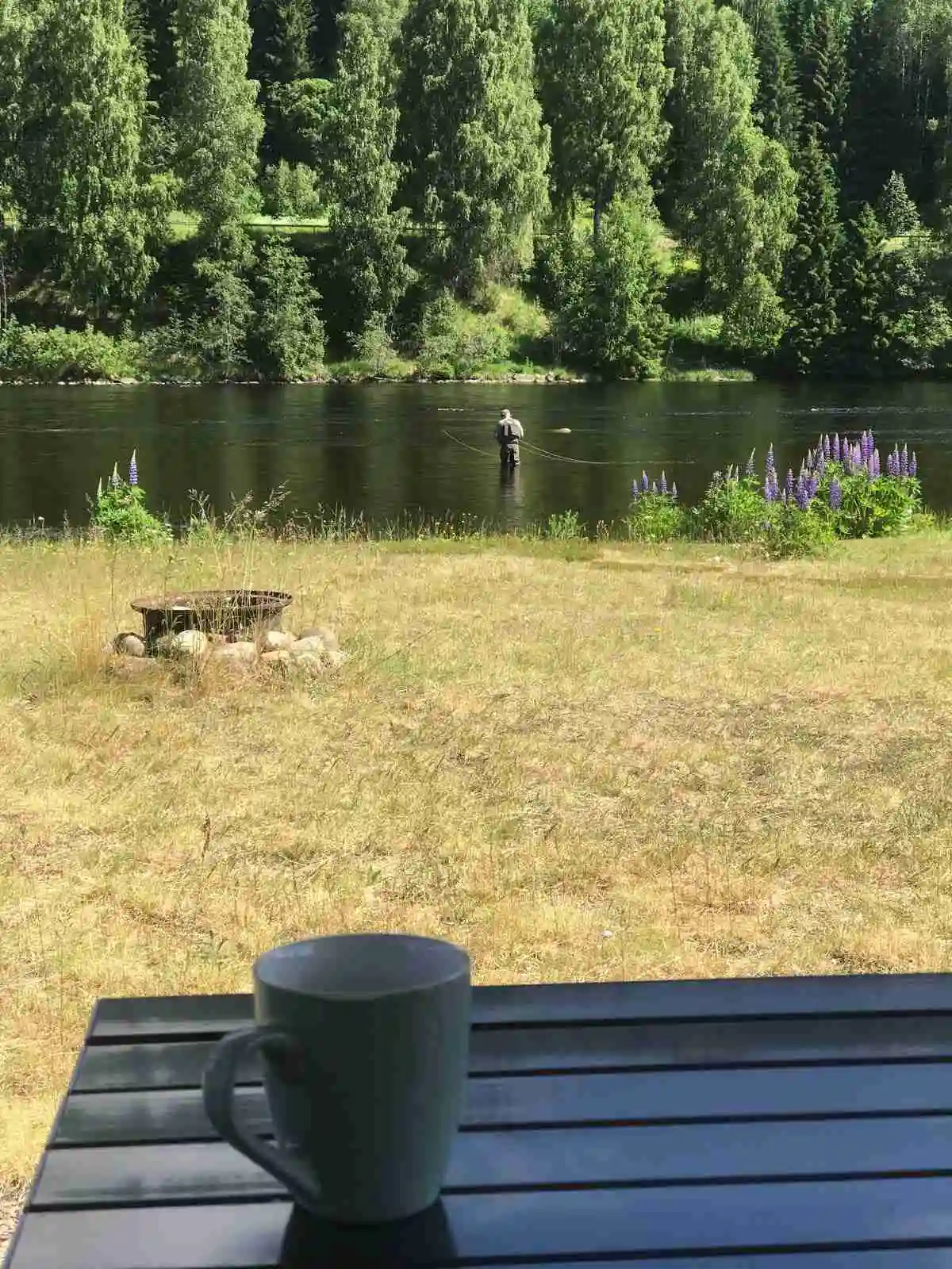 En utomhusscen vid Bråtens camping som visar ett picknickbord med serveringsartiklar, omgiven av en sjöutsikt och gröna omgivningar.