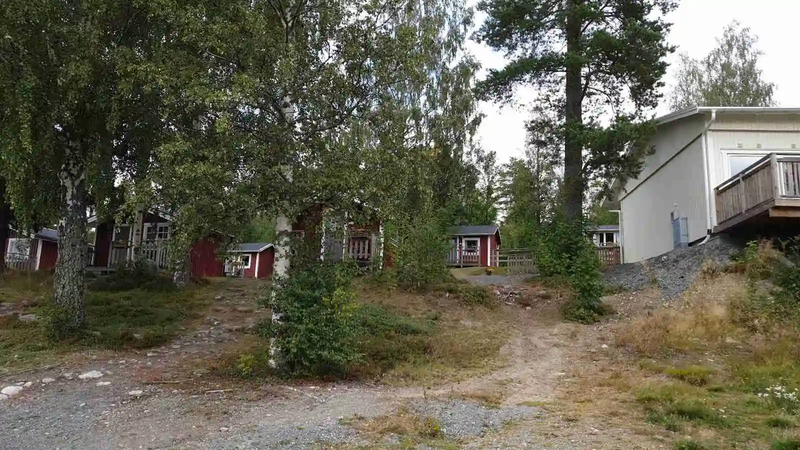 En idyllisk stuga på landsbygden omgiven av grönskande träd och buskar, med en välskött trädgård.