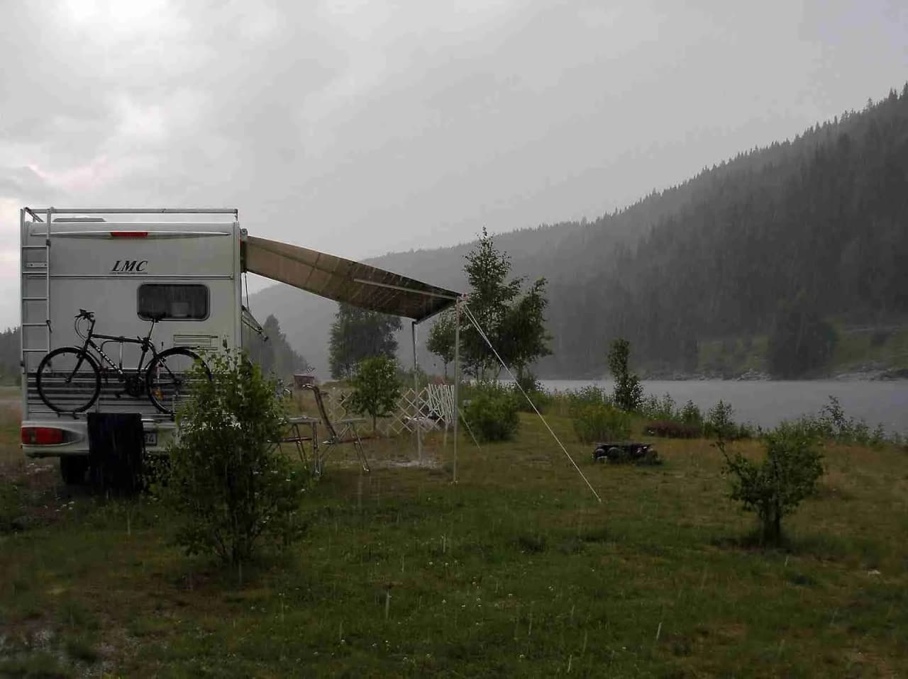 Bild av flera husvagnar och husbilar uppställda vid Bråtens camping, omgivna av grönska och träd, vilket skapar en inbjudande atmosfär för campingentusiaster.
