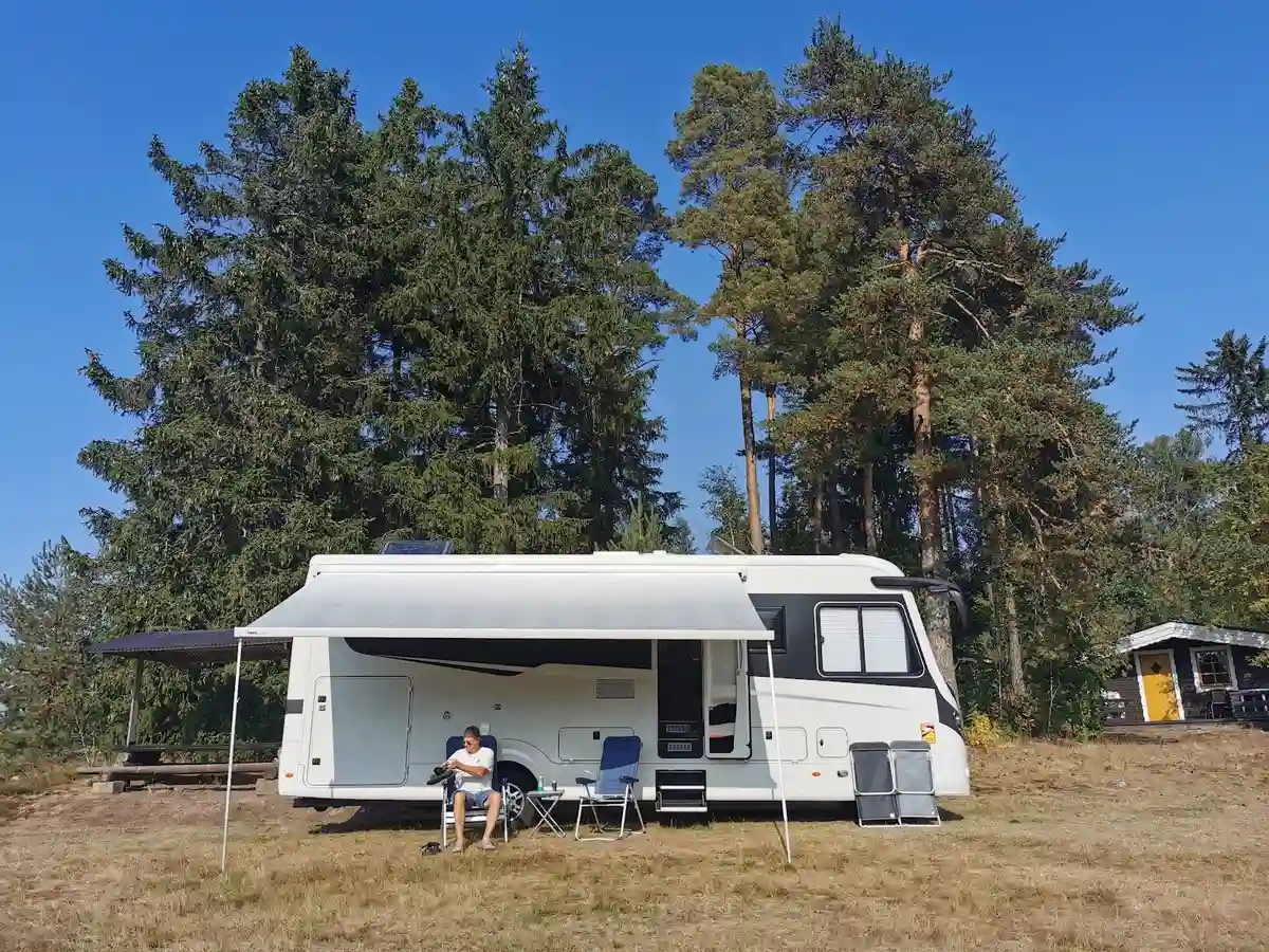 En campingplats i vildmarken med flera husbilar och husvagnar parkerade. Skog i bakgrunden.