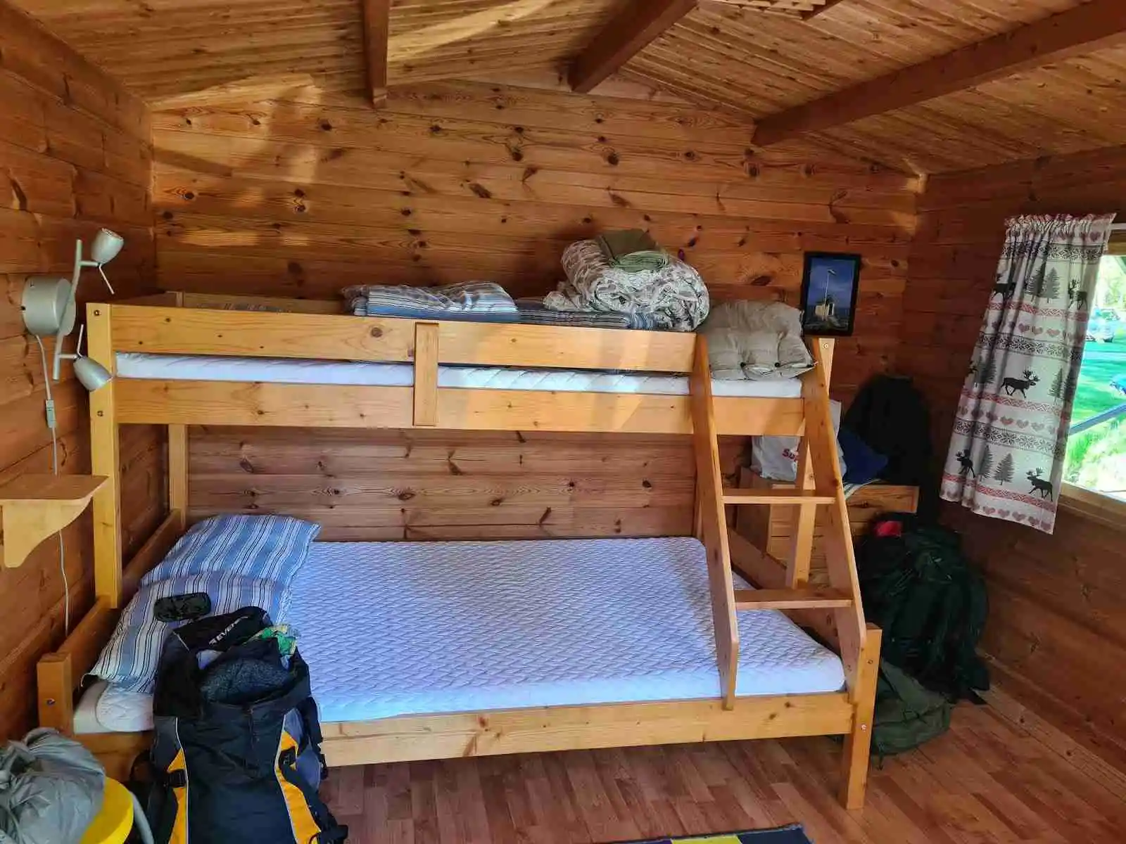 En trästuga med träpaneler står omgiven av frodig skog, vilket ger en mysig och avskild känsla på campingplatsen Tiveden.