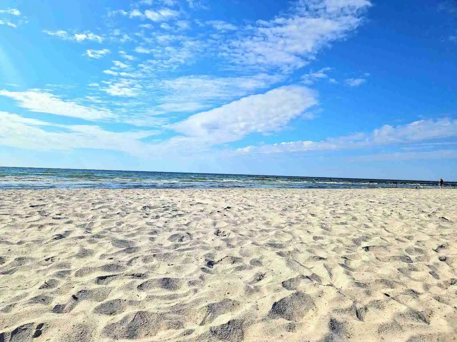Vy över Bingsmarkens camping med en klar blå himmel, och strandlinje där hav möter kust i dagsljus.