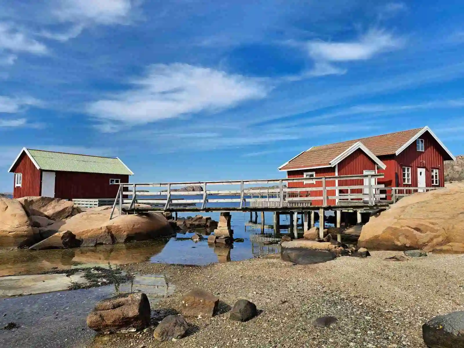 En pittoresk kustbild med trästugor vid stranden, omgiven av klippor och hav vid Hunnebostrands camping och stugor.