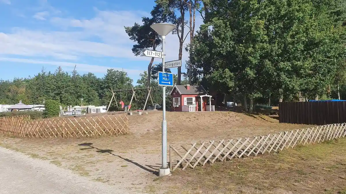 En grusväg leder in till Borrbystrand camping, omgiven av stängsel och stolpar.